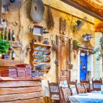 Classic Cretan open Air Restaurant in Chania with Served Tables and Artistically Decorated Walls. Horizontal Image