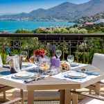 Table with fruits and wine on a summer terrace with sea and mountain views in Crete in Greece.