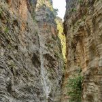 The man walks along the narrow bottom of the gorge next to the mountain river